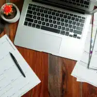 Top view of a coffee cup and laptop on a desk.