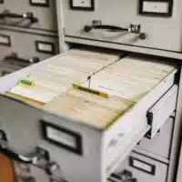Open metal card file drawer with a neatly typed cards visible.,